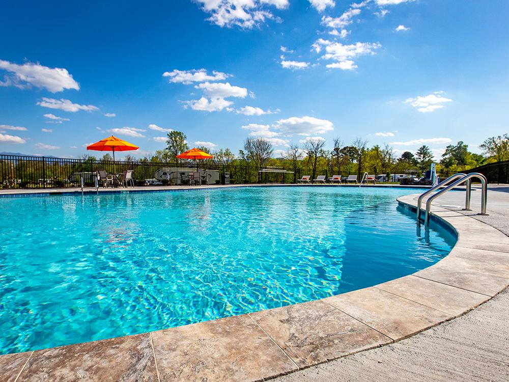 Pool with tables and umbrellas at PIGEON FORGE LANDING RV RESORT