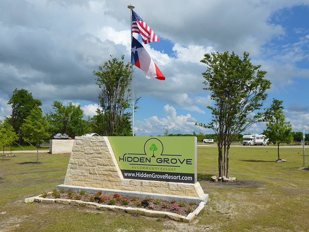 Welcome sign and flags at entrance at HIDDEN GROVE RV RESORT