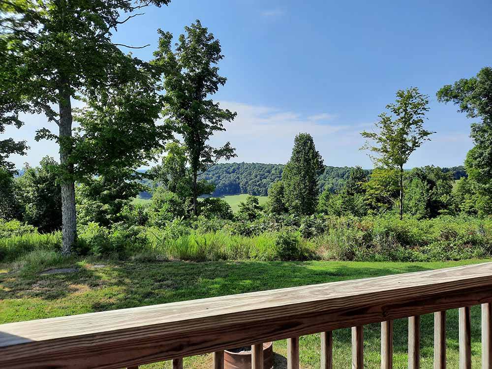 View from a deck overlooking green grass and trees at MOUNTAIN TOP RETREAT CABINS  CAMPGROUND