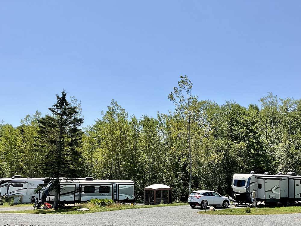 Towable RVs parked onsite with trees in background at WEST BAY ACADIA RV CAMPGROUND