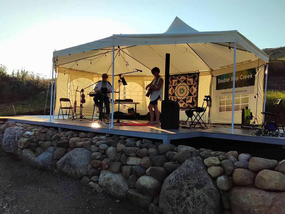 Outdoor music on a stage under a tent at SUMMIT RV RESORT