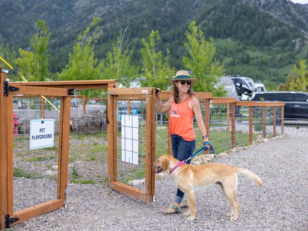 A woman takes her dog to the pet area at ALPINE VALLEY RV RESORT