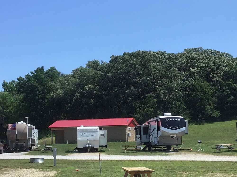 RVs camped with building covered by red roof in background at CROWS NEST RV RESORT