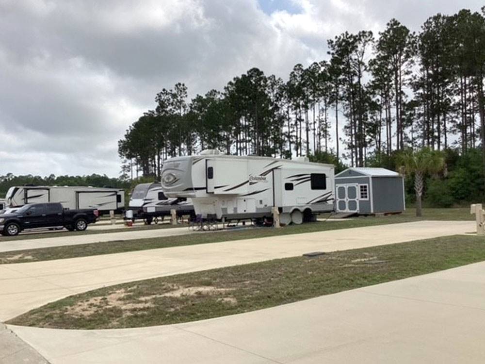 Sites with pines in background at Whispering Pines RV Resort East and West