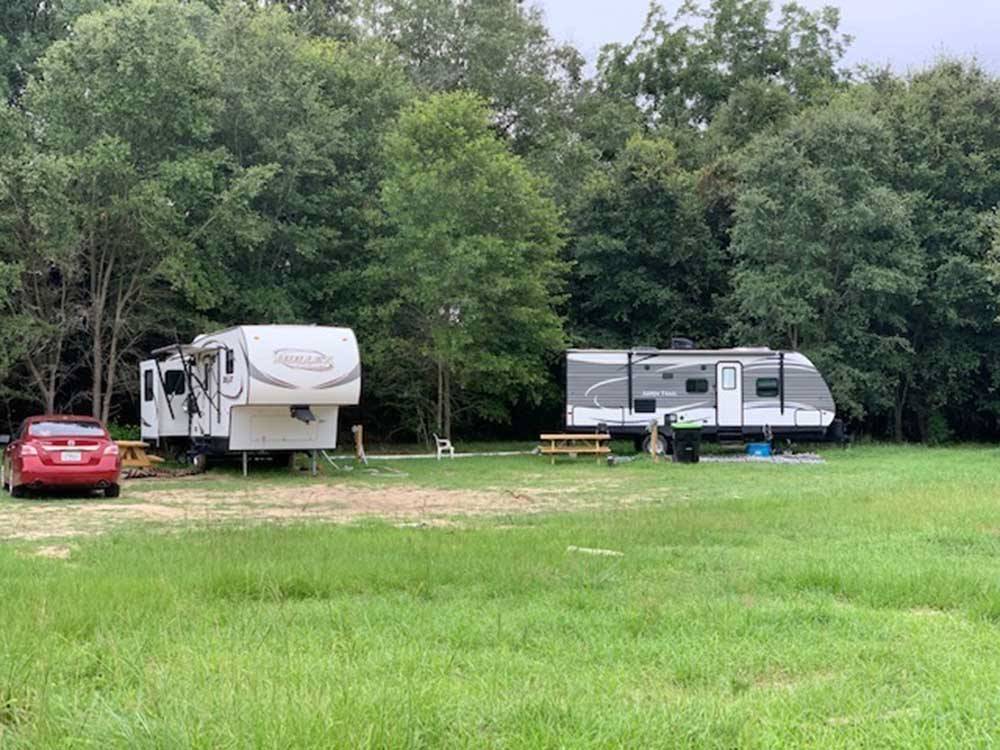 A car and two trailers parked in a grassy area at DREAMLAND RV PARKS