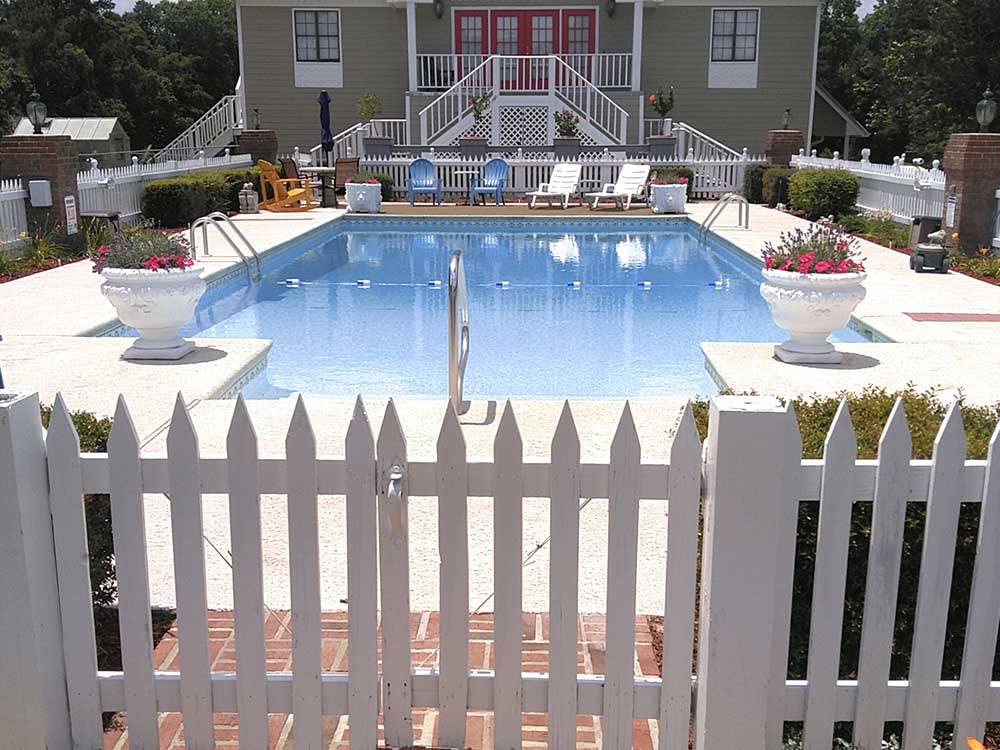 A white picket fence around the swimming pool area at PEBBLE HILL RV RESORT
