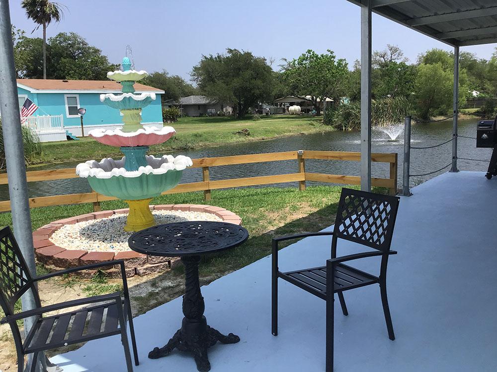 A sitting area near the lake with a fountain at ROCKPORT RV RANCH
