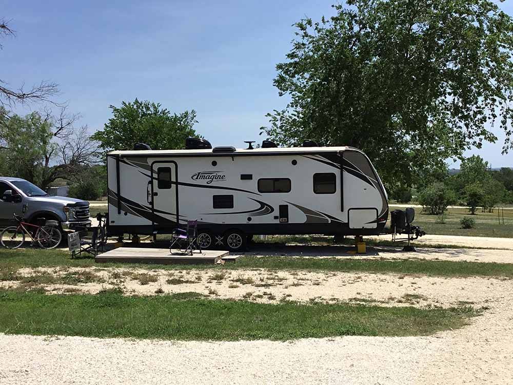 Sandy campsite with a camper at OFF THE VINE RV PARK