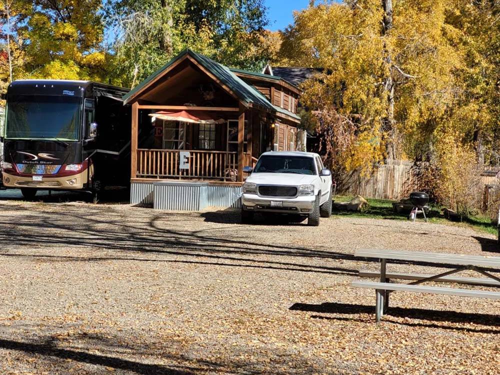Cabin E with a Class A motorhome parked next to it at OUTPOST MOTEL CABINS AND RV PARK