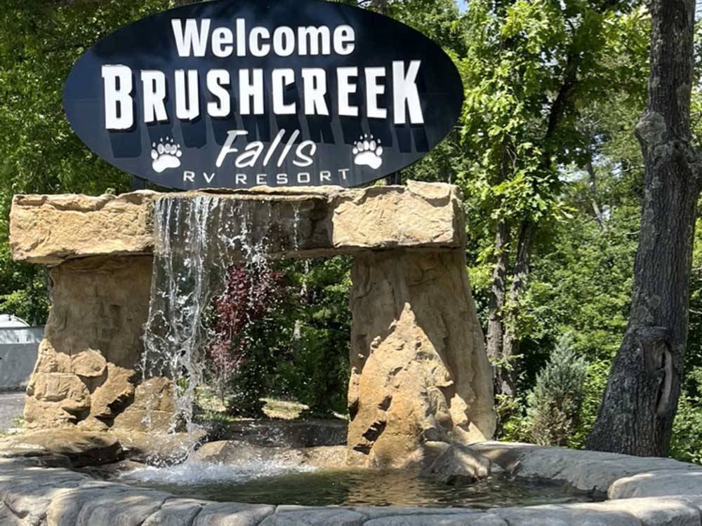 A welcome sign with a waterfall at BRUSHCREEK FALLS RV RESORT