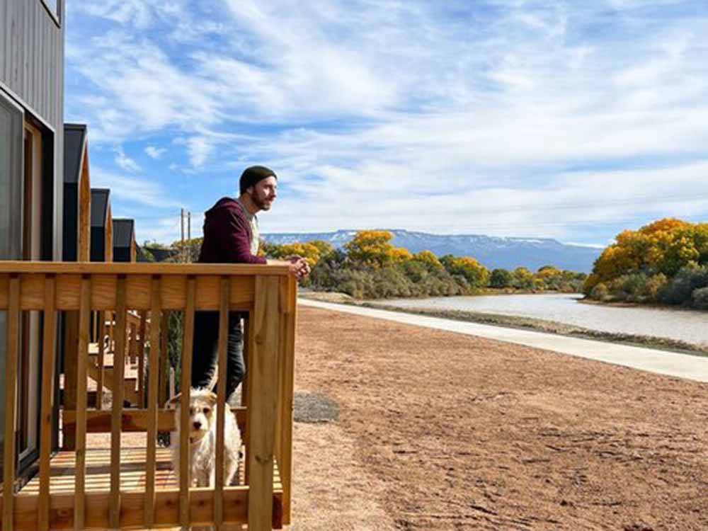 A man and a dog on a deck overlooking the river at CAMP EDDY AND LODGING