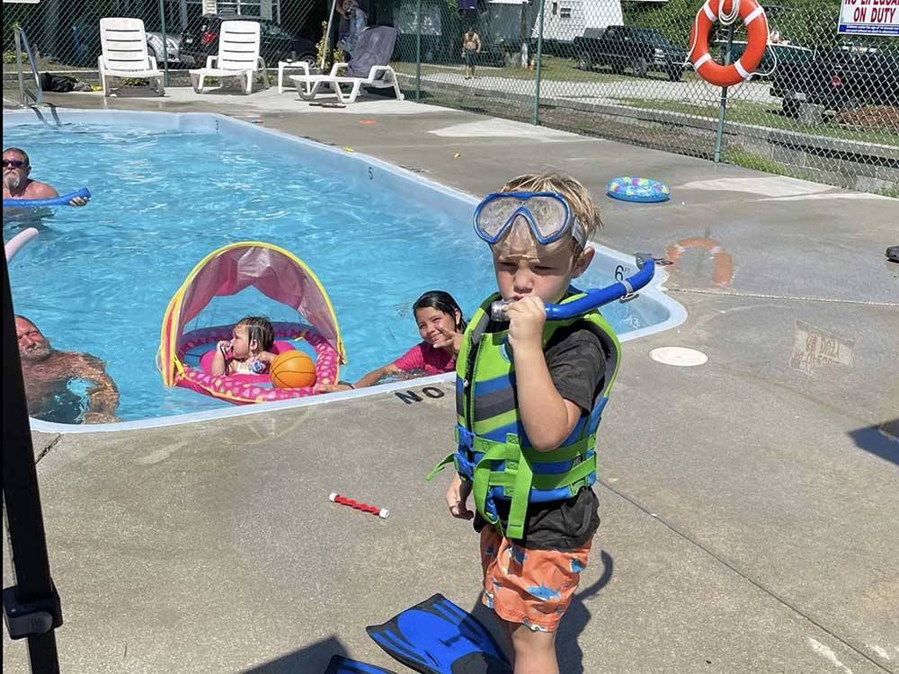 A small boy standing by the pool with a mask and snorkel at BUTTON'S FAMILY CAMPGROUND