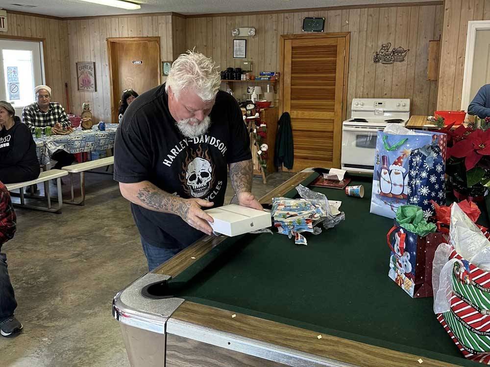 A man opening a Christmas gift at BUTTON'S FAMILY CAMPGROUND