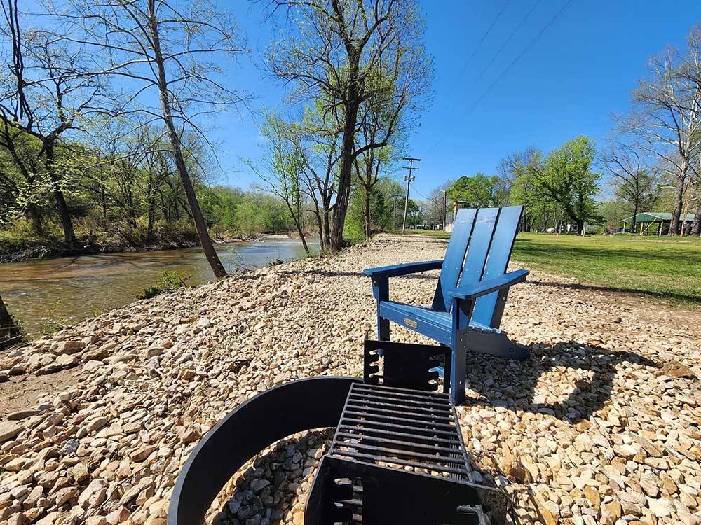 A blue chair and fire pit near the creek at BULL CREEK RV PARK