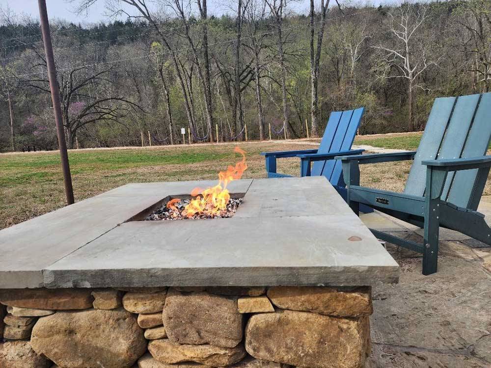 A fire pit burning next to two chairs at BULL CREEK RV PARK