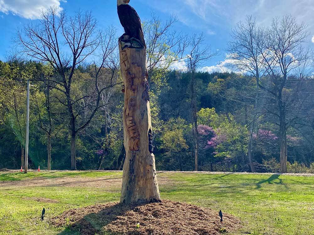 A wooden sculpture of an eagle on a tall tree stump at BULL CREEK RV PARK