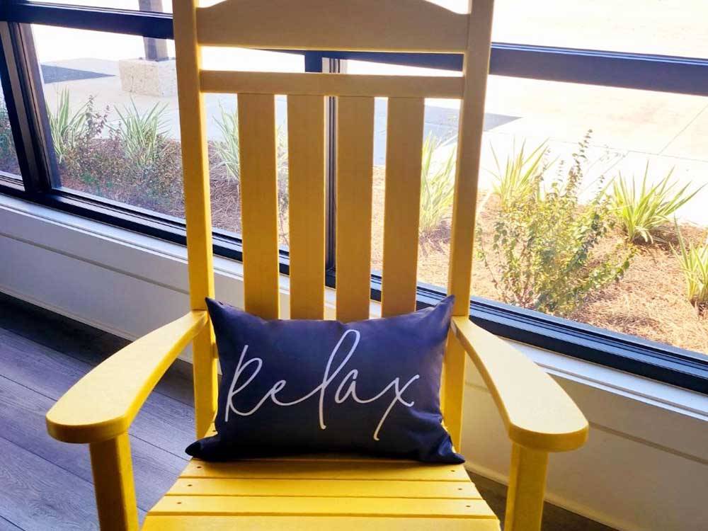 A rocking chair with a pillow that says "Relax" at SAVANNAH LAKES RV RESORT