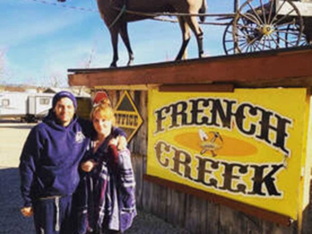 A couple standing in front of the campground sign at FRENCH CREEK RV PARK AND CAMPGROUND