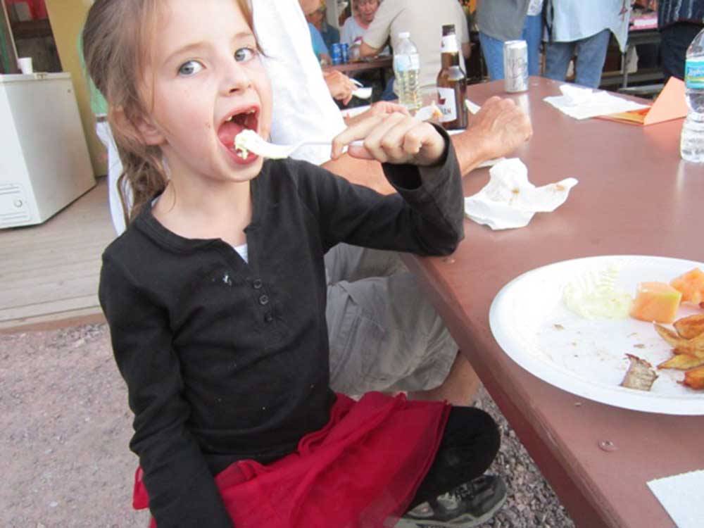 A girl eating food at a table at FRENCH CREEK RV PARK AND CAMPGROUND
