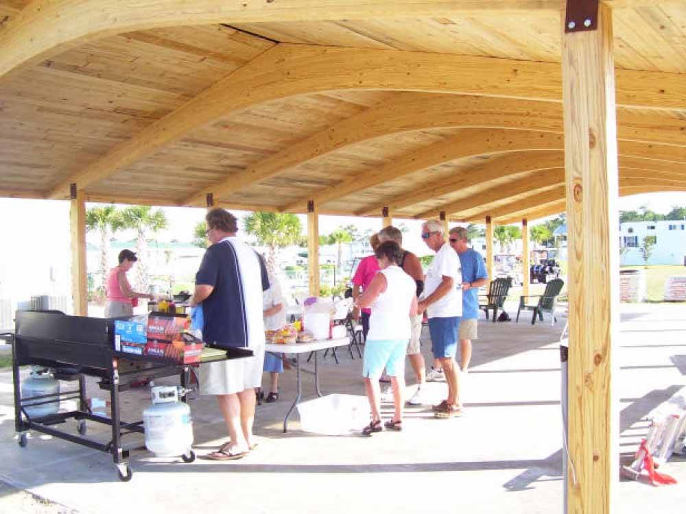 Campers line up for buffet under wooden canopy at TOPSAIL SOUND RV PARK