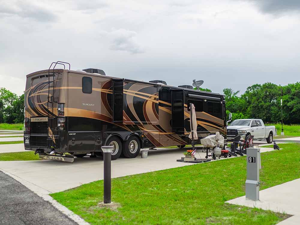 A motorhome parked in a paved site at THE HILL TOP AT BRENHAM RV RESORT