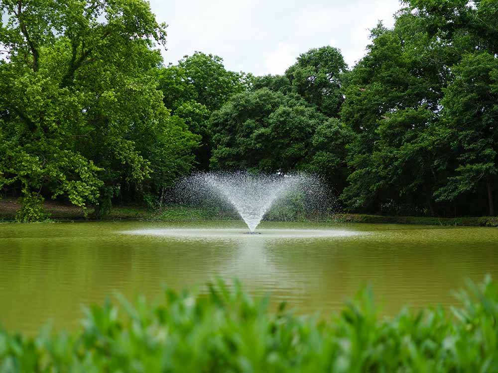 A fountain in the pond at THE HILL TOP AT BRENHAM RV RESORT