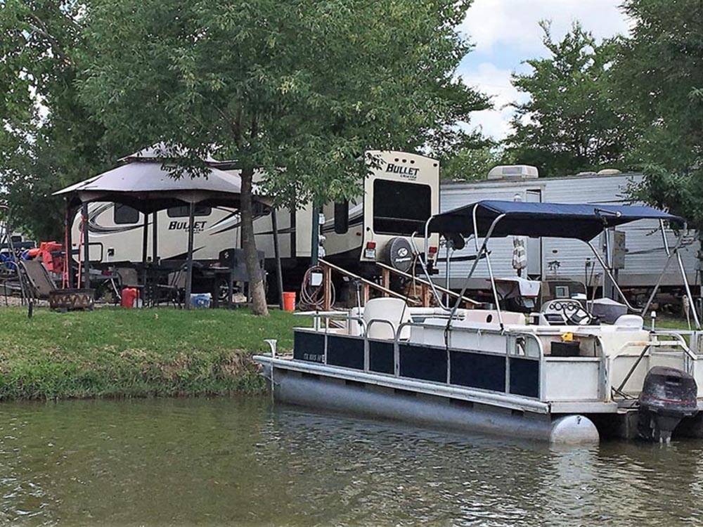Pontoon boat docked next to RV sites at LAKE CONROE RV CAMPGROUND BY RJOURNEY