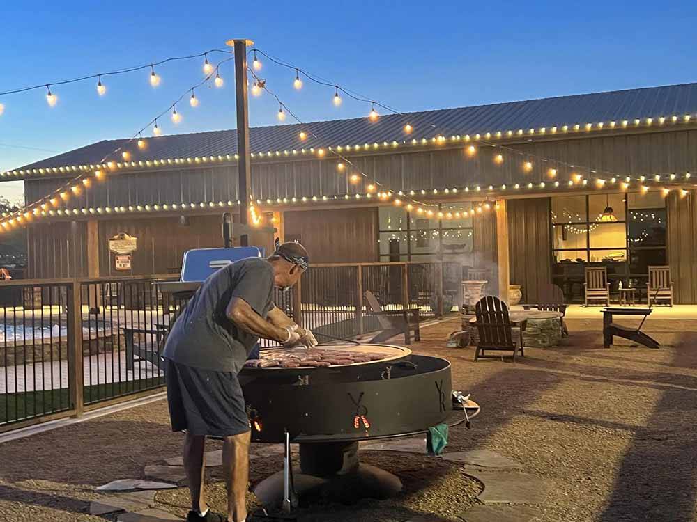 A man cooking on a large BBQ at YELLOW ROSE RV RESORT