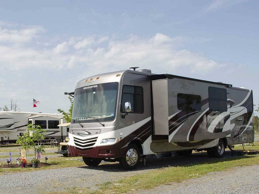 A motorhome parked in a gravel site at SUN OUTDOORS CHINCOTEAGUE BAY