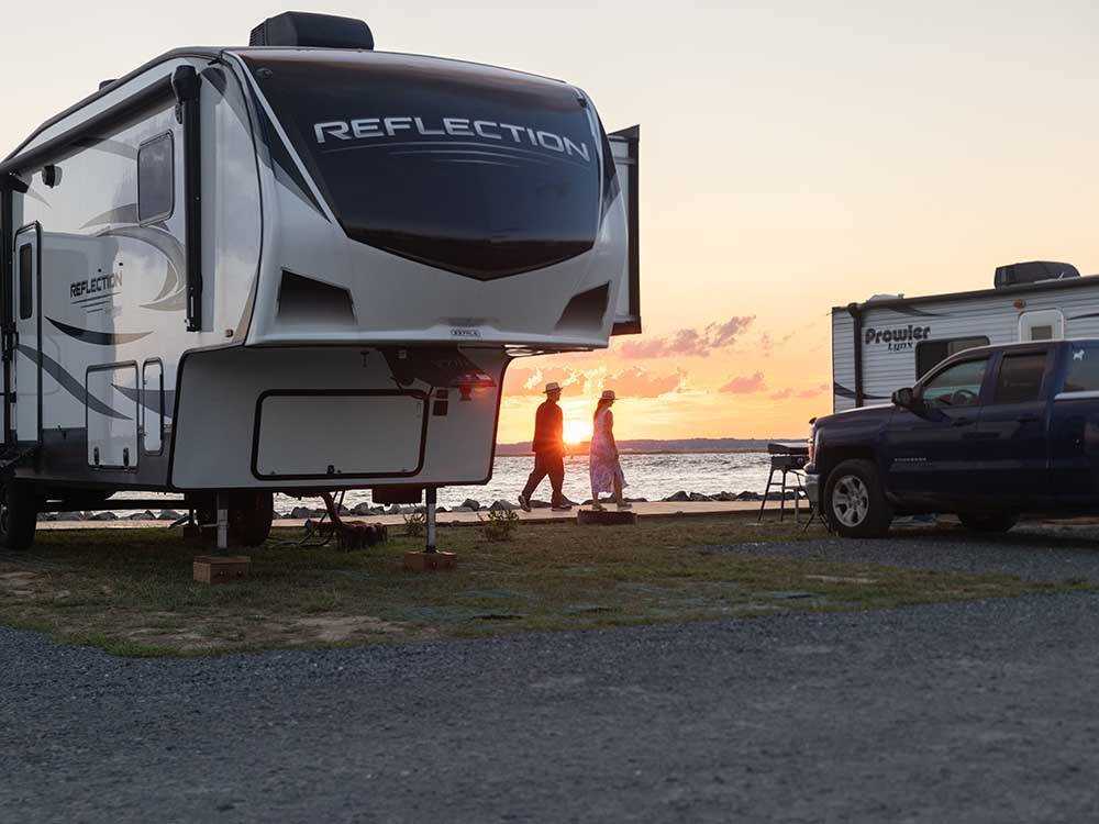 A couple passing by a parked fifth wheel at SUN OUTDOORS CHINCOTEAGUE BAY