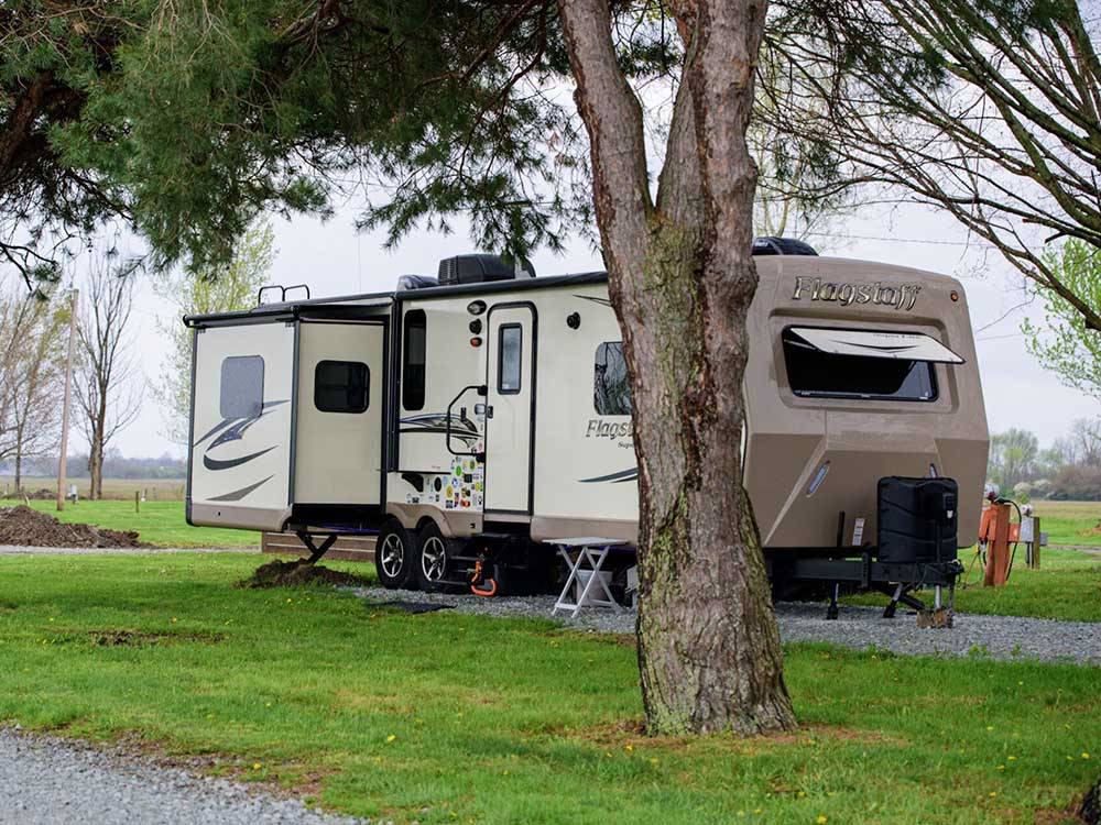 A travel trailer parked in a gravel site at MYSTIC WATERS FAMILY CAMPGROUND