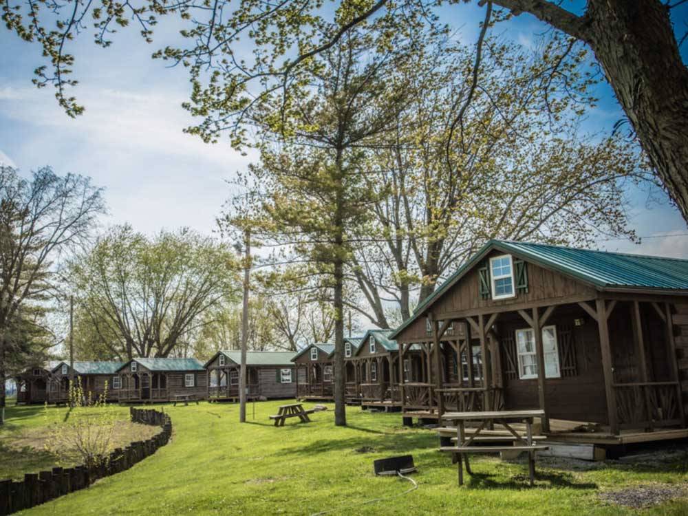 A row of cabins with picnic benches at MYSTIC WATERS FAMILY CAMPGROUND