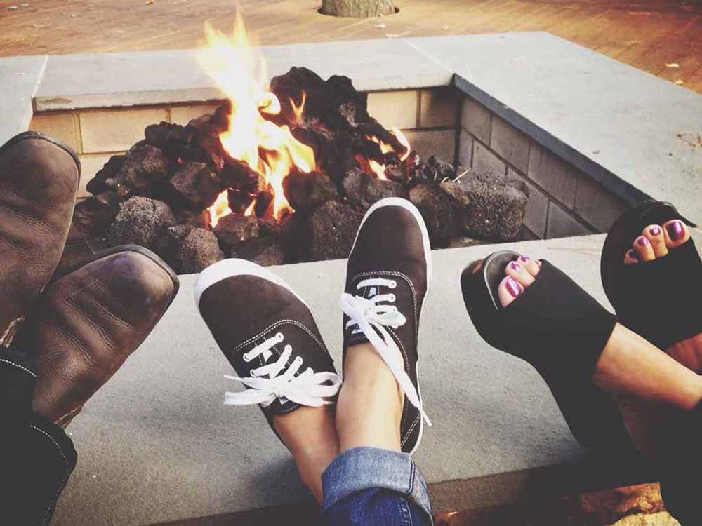 Three people's feet by the fire pit at JETSTREAM RV RESORT AT WHARTON