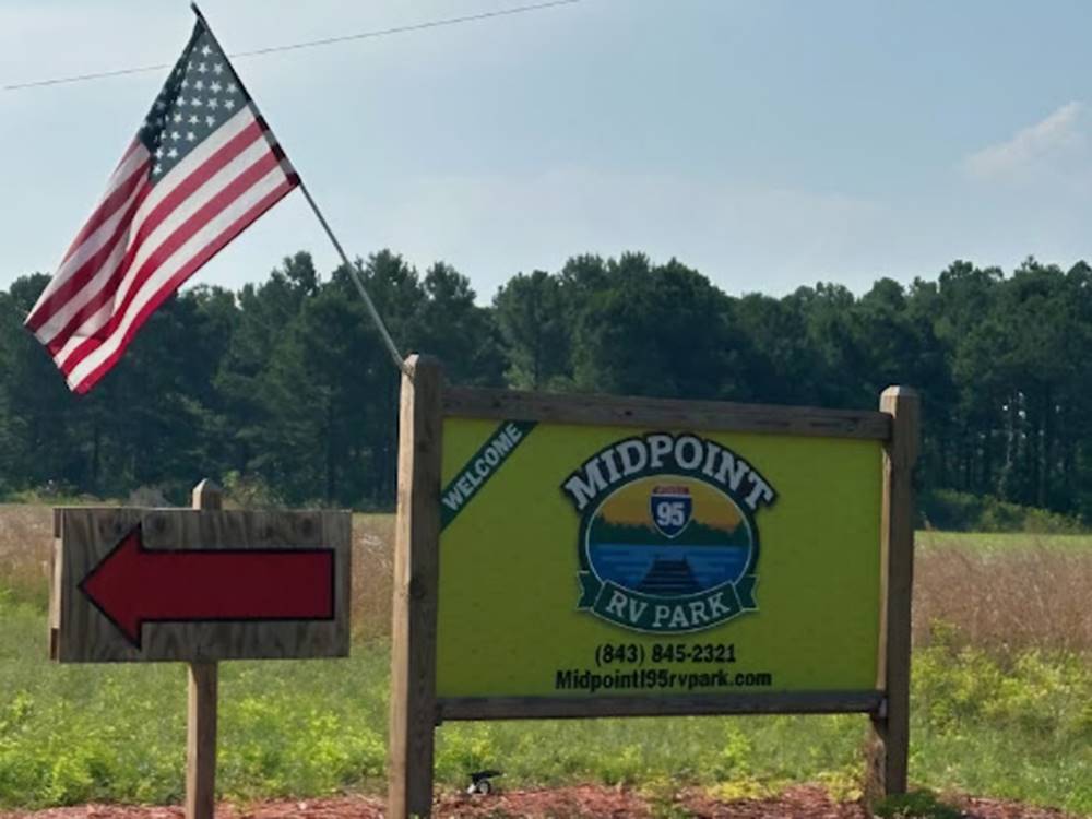 Entrance sign with red arrow and American flag at Midpoint I-95 RV Park