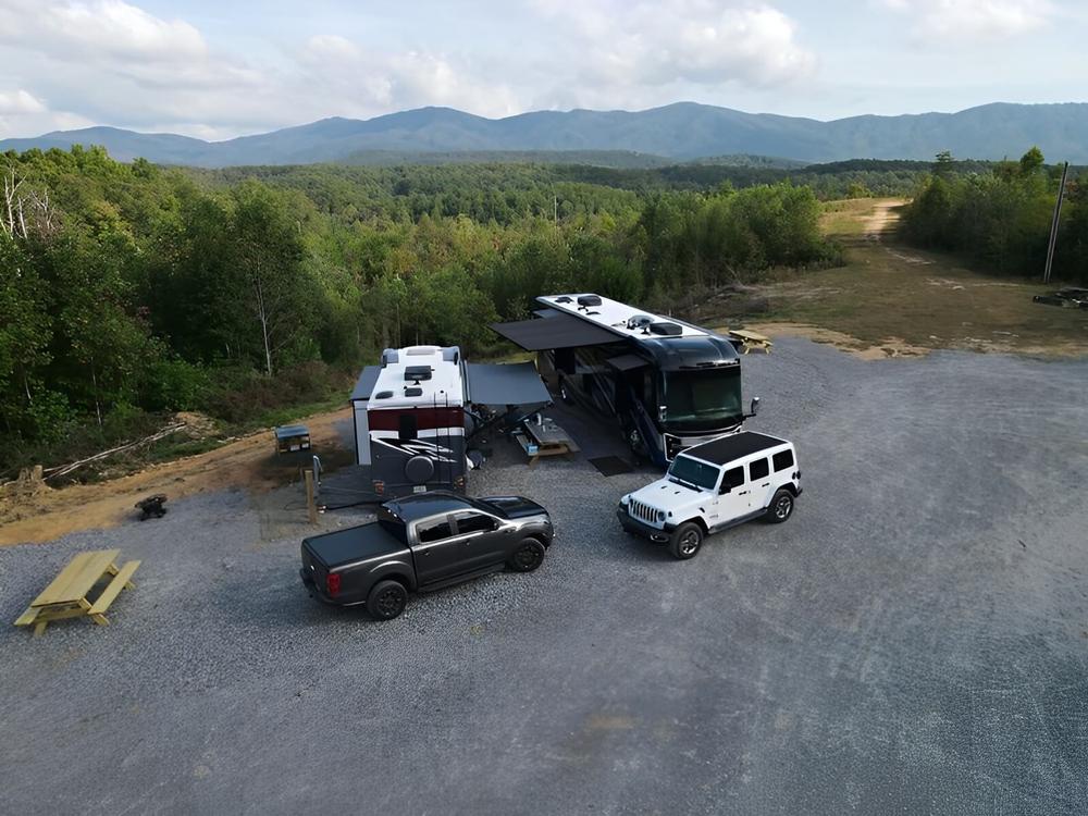 RVs and cars parked in a site over looking a forested valley