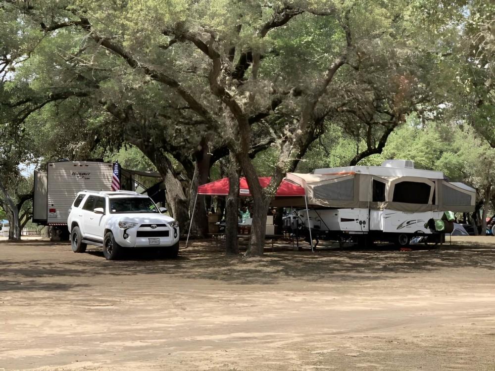RV's parked under trees at Nueces River RV and Cabin Resort