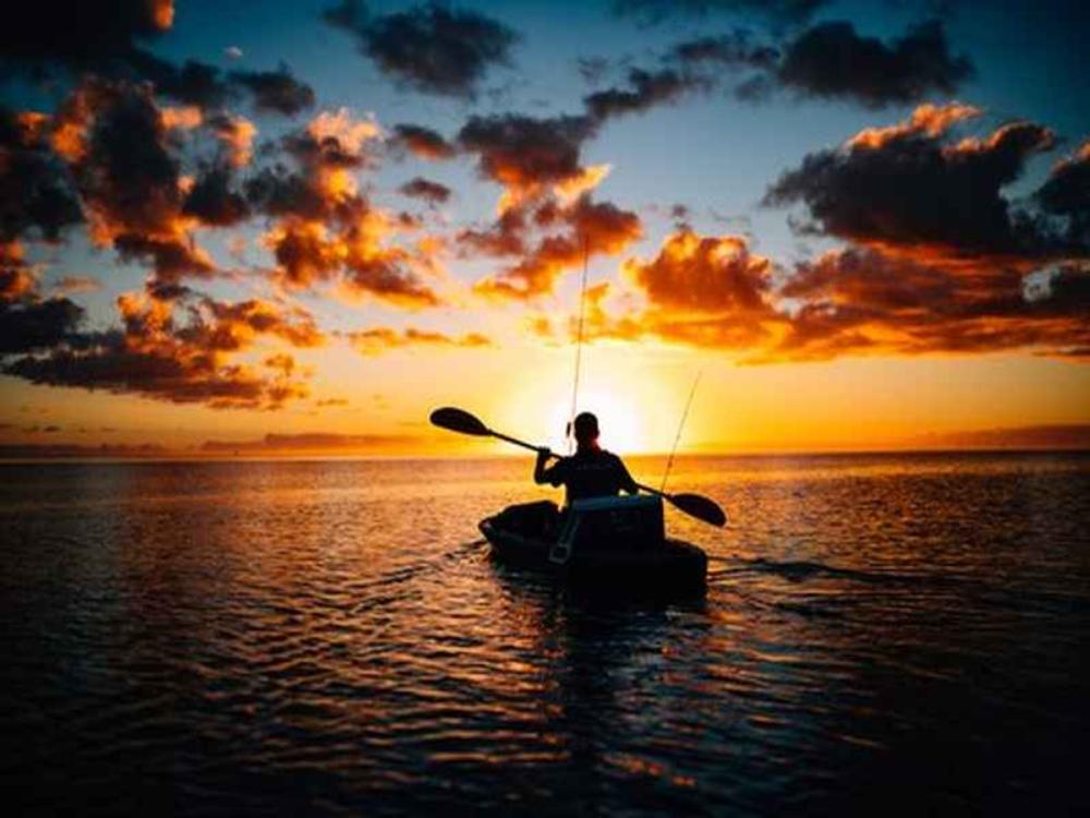 Person in a boat during sunset at I'm on Vacation - RV + Camper Retreat