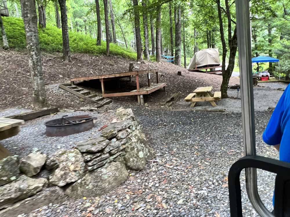 A fire pit next to a tent site at PLUMTREE CAMPGROUND AND RETREAT