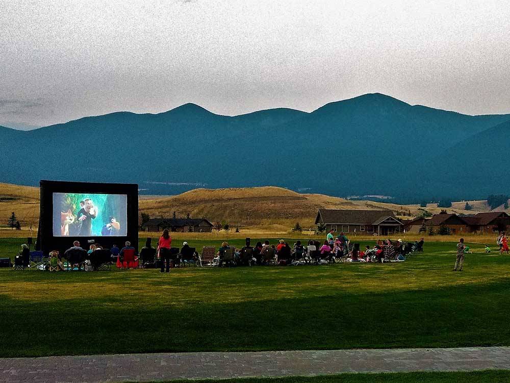 Guest watching a large screen movie outside at INDIAN SPRINGS RANCH GOLF & RV RESORT