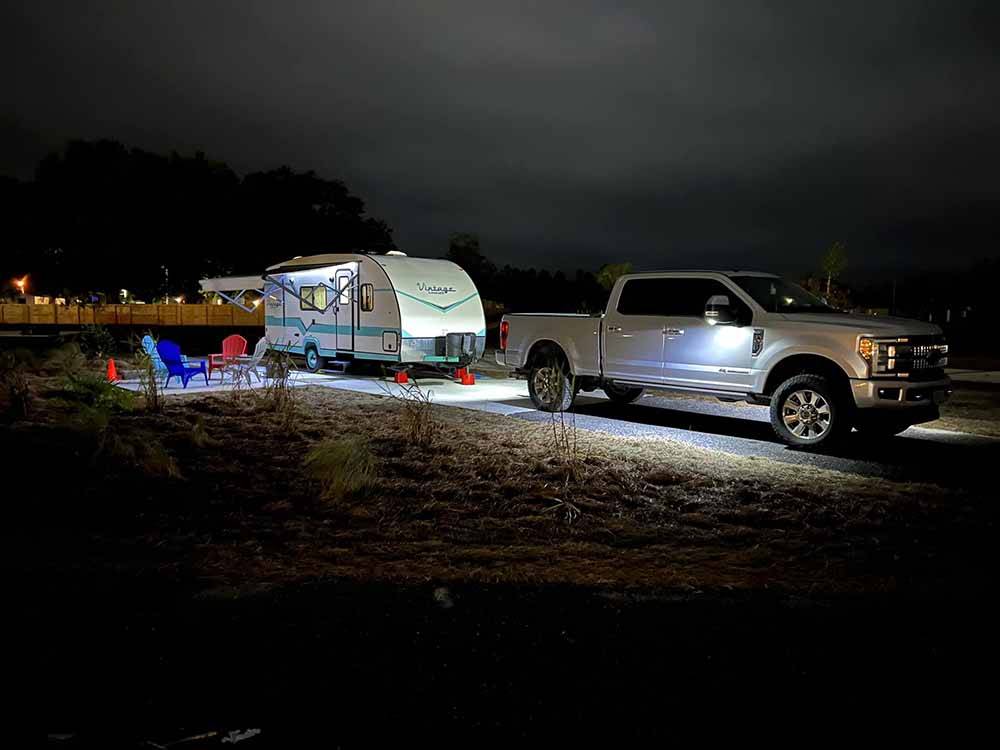 A truck and travel trailer in a RV site lit up at night at at THE STATION RV RESORT