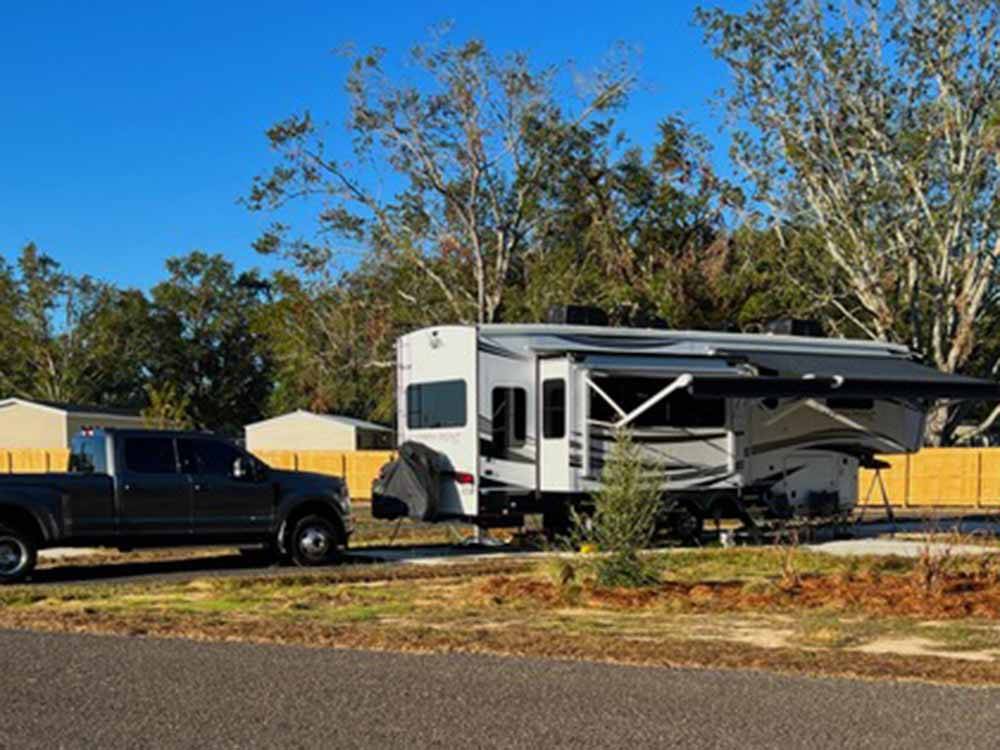 A truck and fifth wheel in a paved site at THE STATION RV RESORT