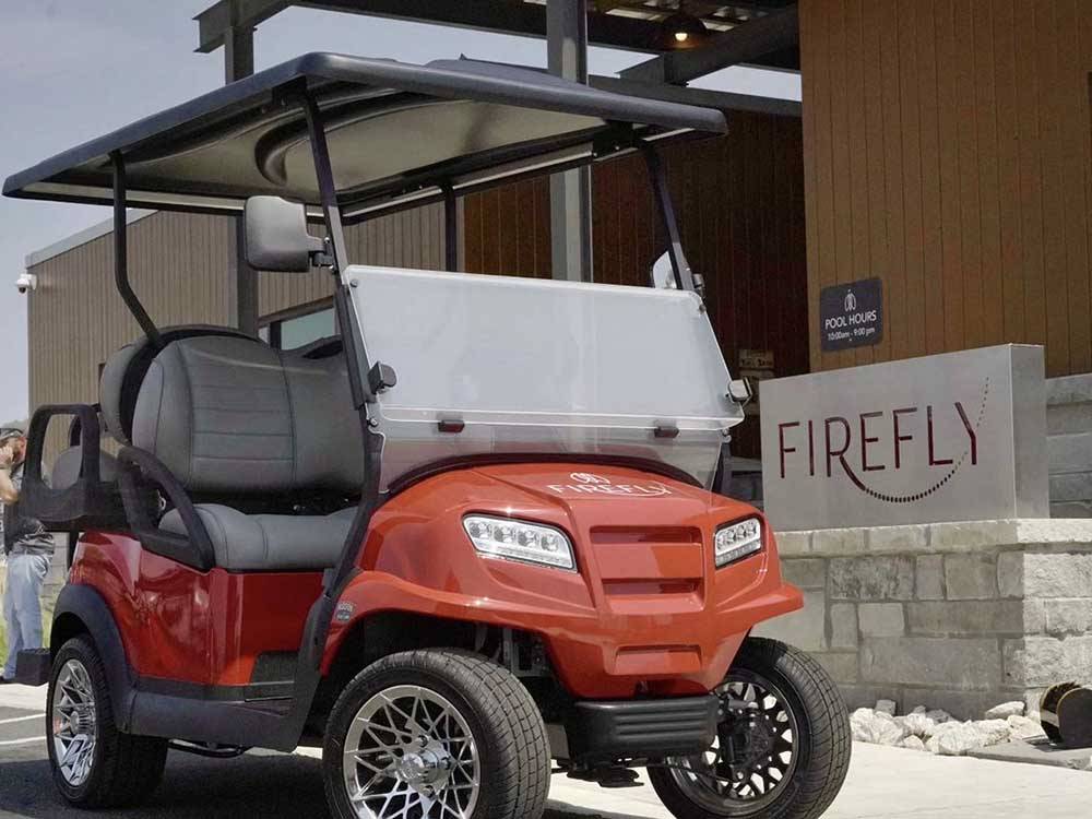 A golf cart parked in front of the pool house at FIREFLY LUXURY RV RESORT
