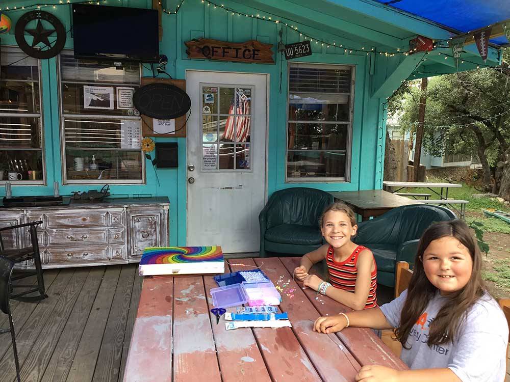 Two girls doing crafts by the office at REBECCA CREEK CAMPGROUNDS