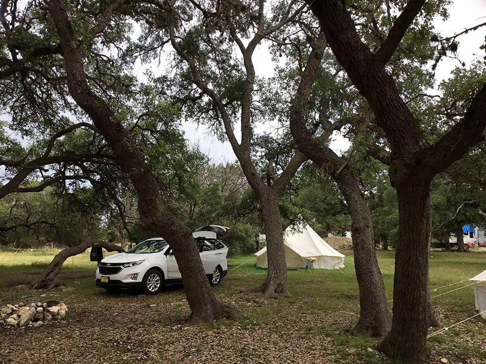 A car and glamping tent under trees at REBECCA CREEK CAMPGROUNDS