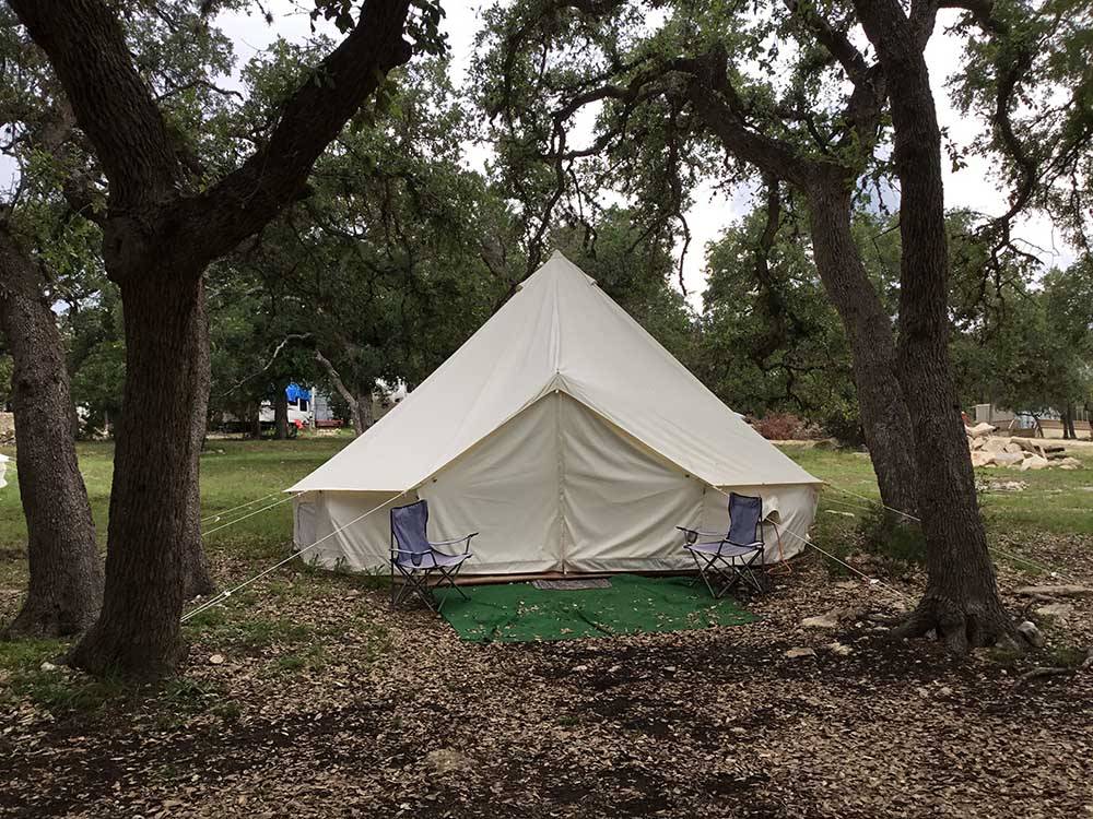 A glamping tent with two chairs in front at REBECCA CREEK CAMPGROUNDS