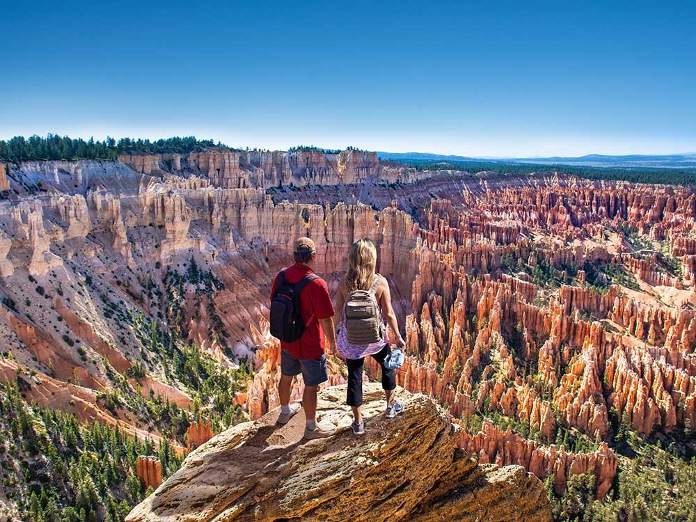 A couple standing on a cliff looking out at Bryce Canyon National Park nearby at BRYCE CANYON SHADOWS CAMPGROUND