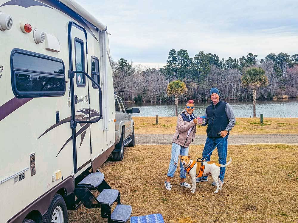 A couple and dog in front of their trailer at BELLS MARINA RV RESORT