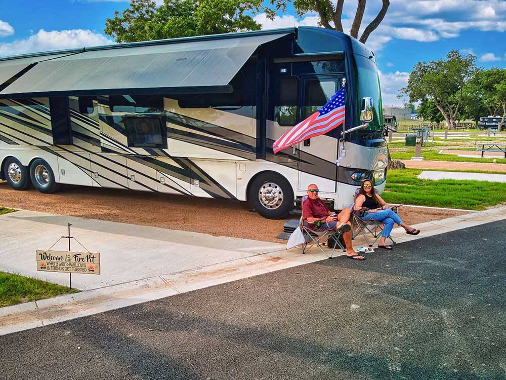 A couple sitting in front of their motorhome at CANOPY LUXURY RV RESORT