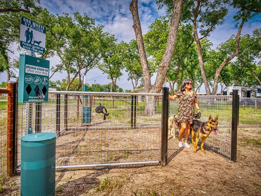 A lady and her dog exiting the dog area at CANOPY LUXURY RV RESORT