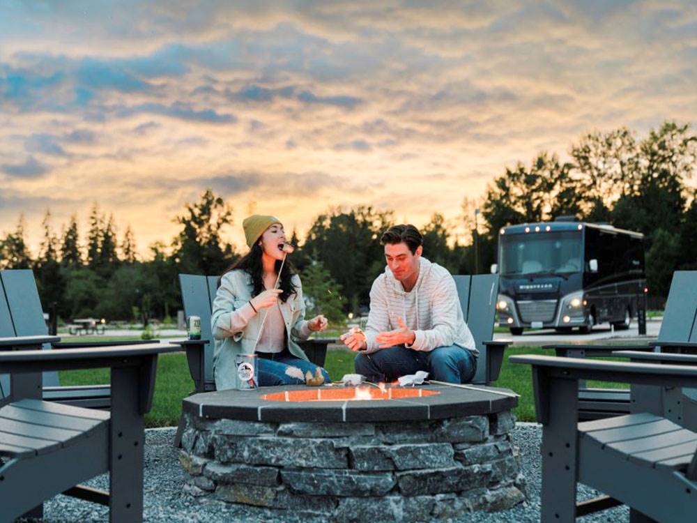 A couple roasting marshmallows in the fire ring at ANGEL OF THE WINDS RV RESORT